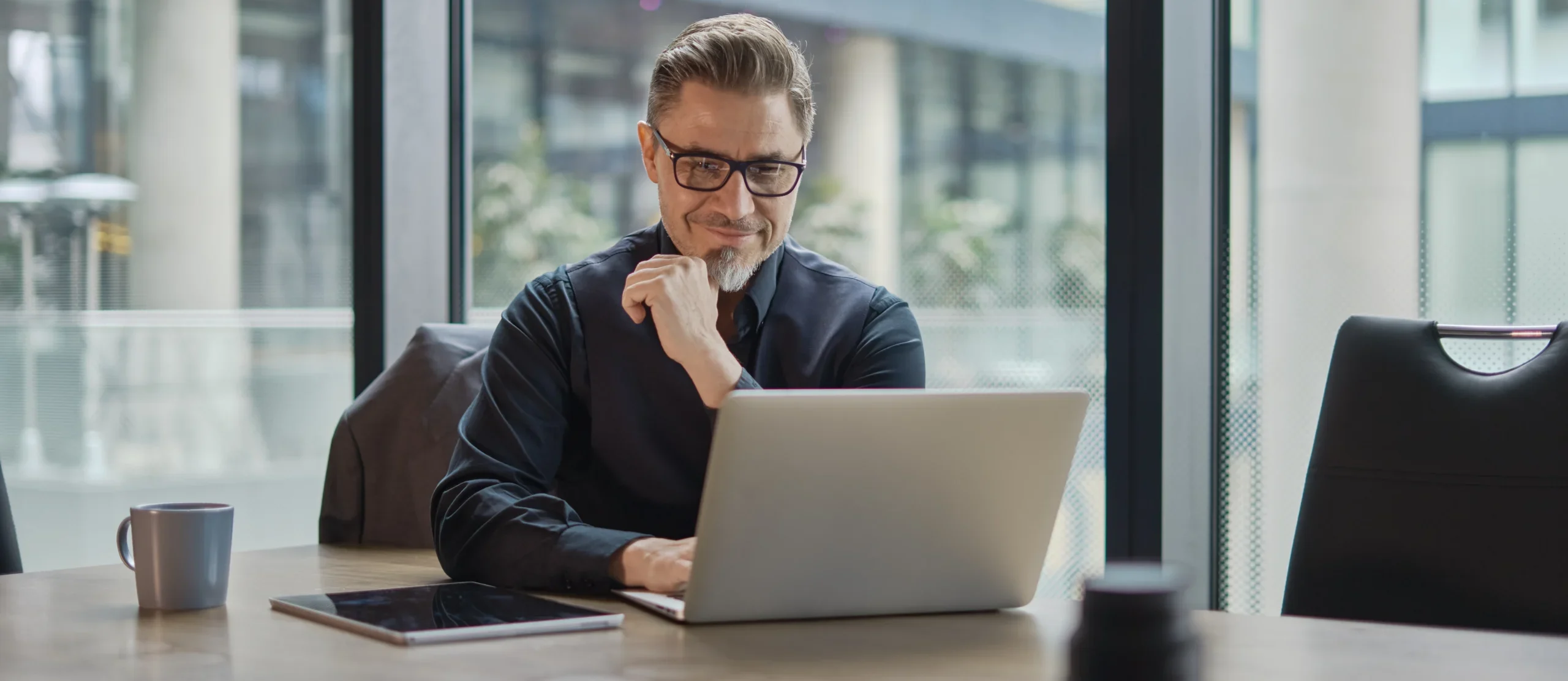 Businessman using laptop computer in office. Happy middle aged man, entrepreneur, small business owner working online.