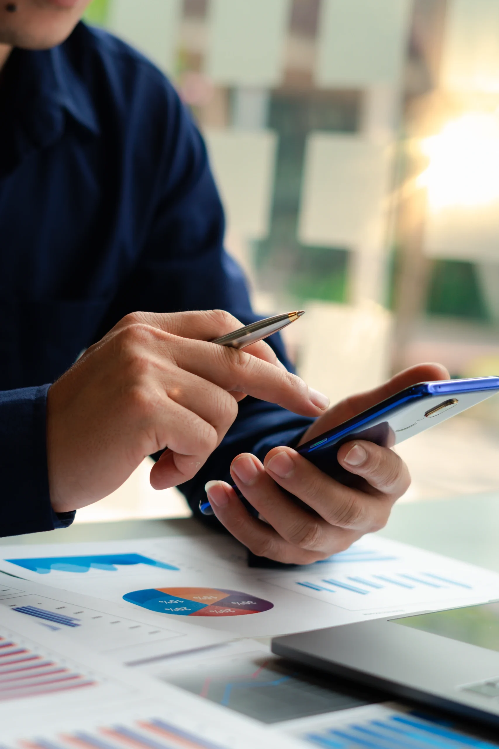 businessman hand using smartphone technology calculate for analysis and budget financial accounting with growth statistics chart and graph on paper work